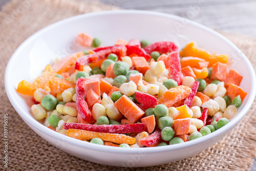Mixed frozen vegetables in a plate on wooden table