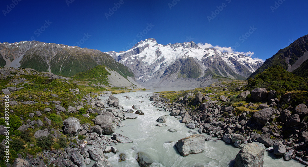 Beautiful natural landscape. Rocks, river and snowy mountains in the background. Walking the Hooker Valley Track, Mount Cook, New Zealand. Enjoy the summer. Hiking and walking in the nature. 