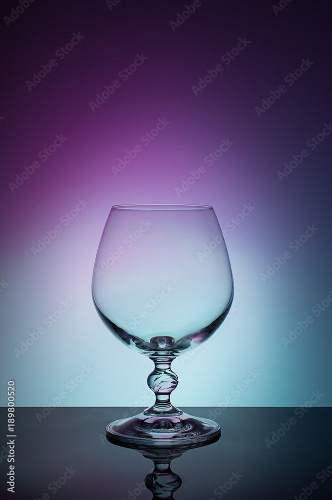 Wineglass on a color background with a black vignette. A tall Wineglass with a thin stalk Wineglass on a color background with a black vignette. A tall Wineglass with a thin stalk