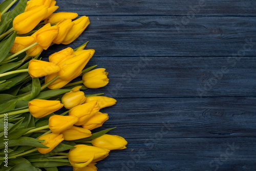 Fototapeta Naklejka Na Ścianę i Meble -  Yellow tulips on blue wooden background. Spring background with tulips, copy space for text. Flat lay, top view.