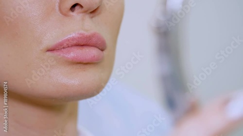 clinic, a beauty salon, a large plan of the lips, the doctor shows the patient a lip zone for injection of hyaluronic acid, discuss the procedure of lip augmentation photo