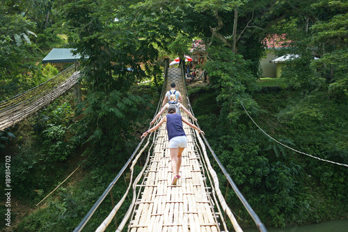 Young tourists cross the scary hand crafted bamboo bridge in Bohol , the Philippines