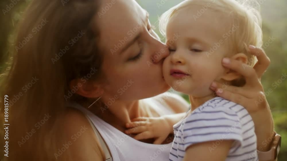 Young mom holding on hands little baby which looking into camera Young mom holding on hands little baby which looking into camera