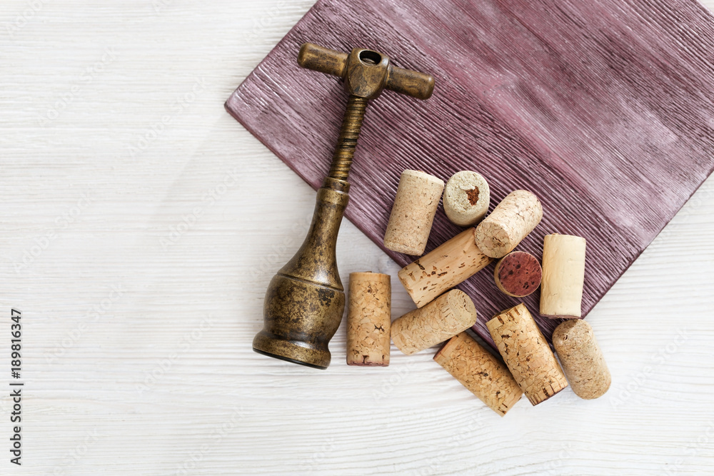 Metal retro corkscrew and heap used wine corks on wooden table. Copy space. Top view. Flat lay.