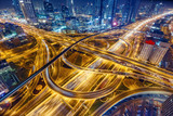 Aerial view of big highway interchange with traffic in Dubai, UAE, at night. Scenic cityscape. Colorful transportation, communications and driving background.