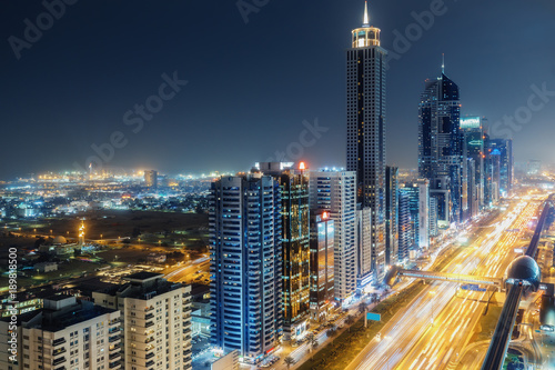 Scenic nighttime skyline of big cmodern city with illuminated skyscrapers. Aerial perspective of downtown Dubai, UAE. Multicolored travel background. © Funny Studio