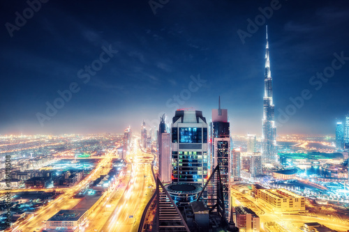 Scenic nighttime skyline of big cmodern city with illuminated skyscrapers. Aerial perspective of downtown Dubai, UAE. Multicolored travel background.