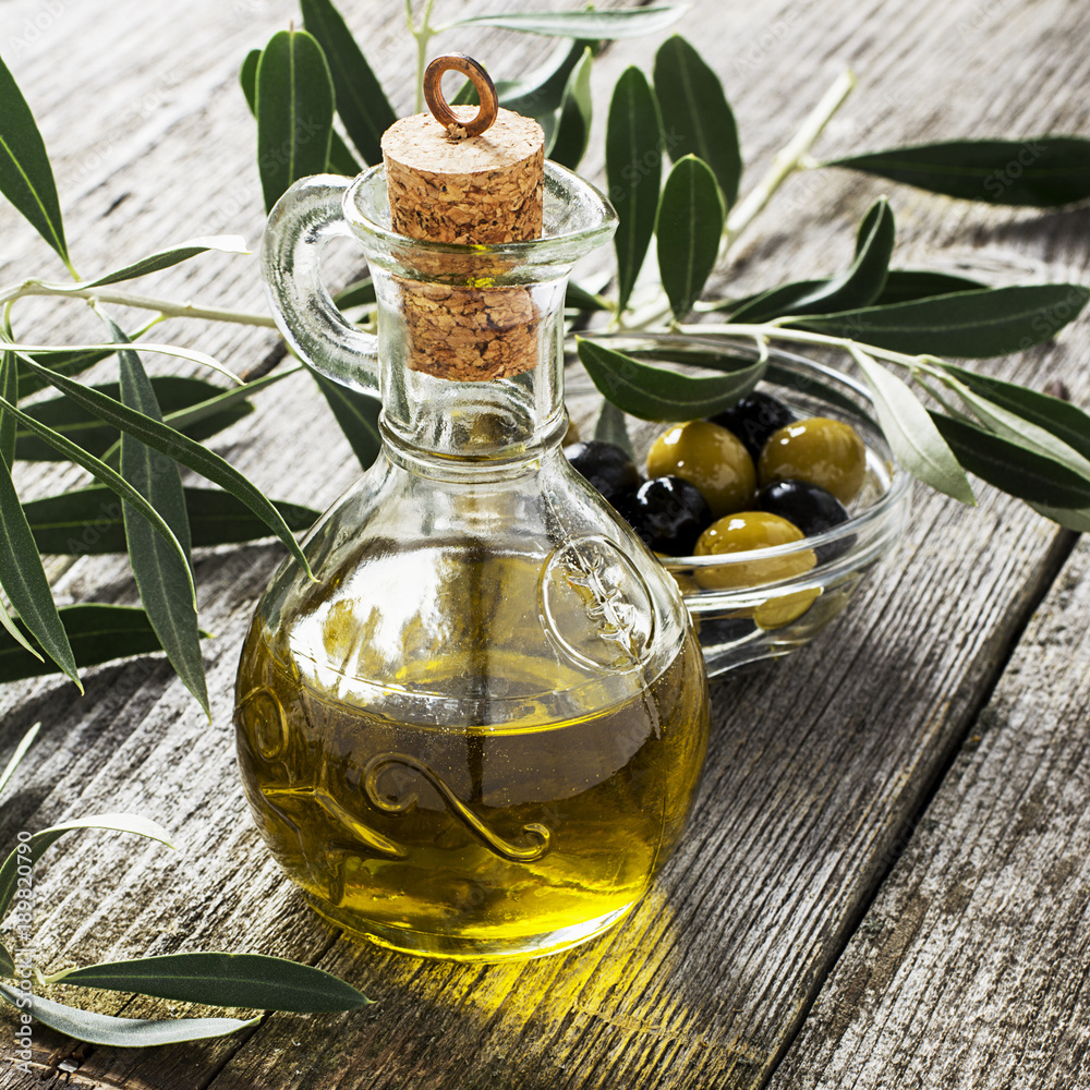 Jug with extra virgin olive oil on olive cutting board surrounded by  branches of the olive tree and olives. Selective focus. The concept of a  healthy natural food Stock Photo | Adobe