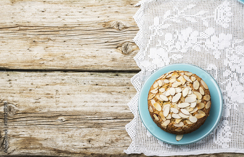 Simple homemade pecan pie decorated with petals of almond with a wooden background Serving Easter used blue and yellow colors, quail eggs, lavender flowers, vintage linen tablecloth handmade.