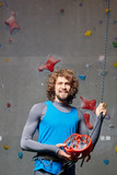 Young climber with safety helmet in hands looking at camera before training