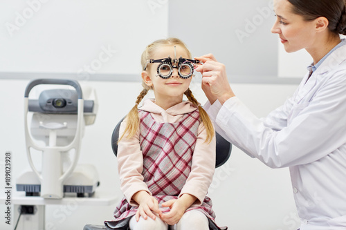 Professional oculist choosing lens for eyeglasses for her little patient