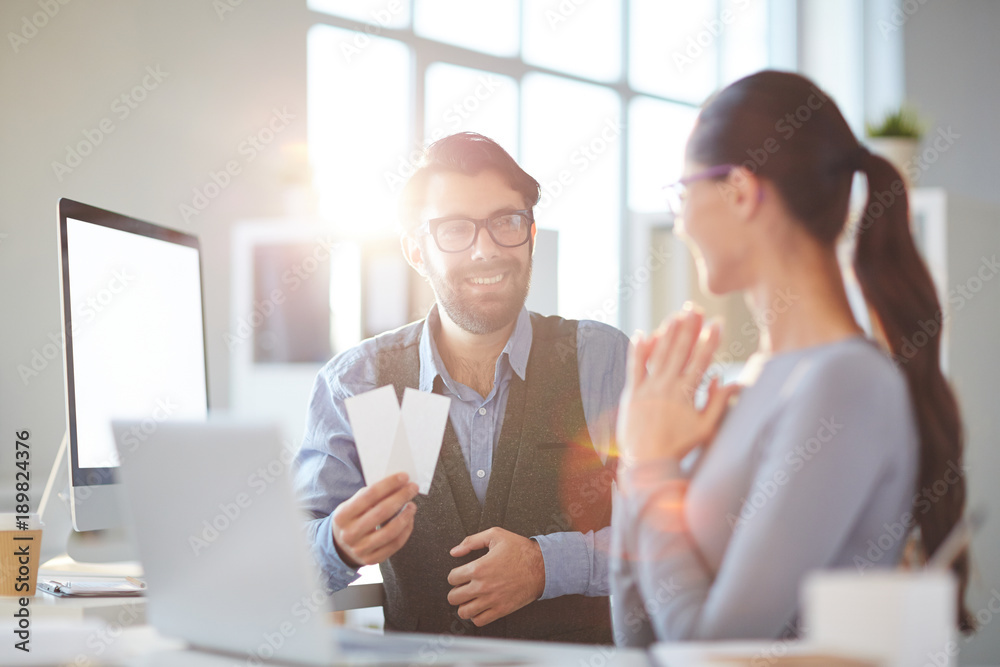 Obraz premium Young employee with two tickets offering his colleague to go to concert or performance in the evening