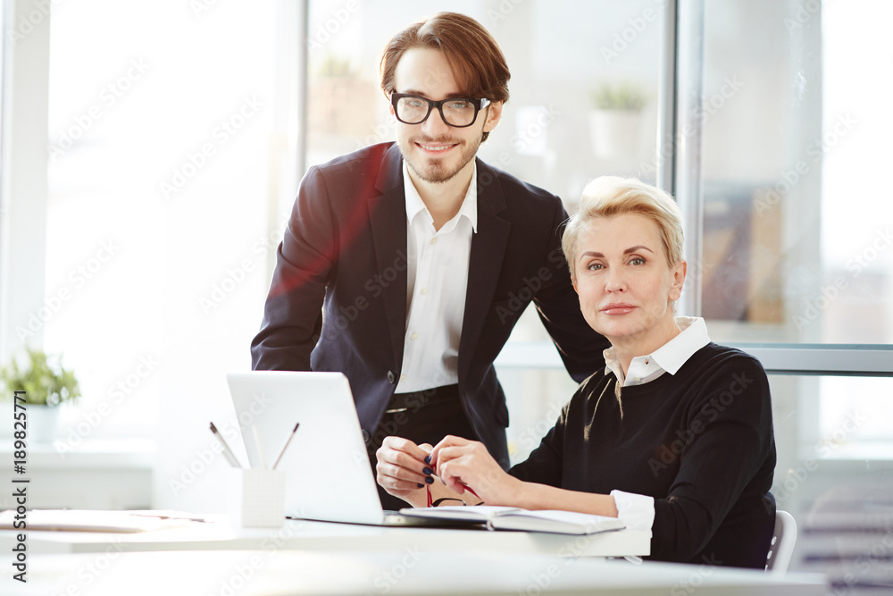 Young specialist and experienced colleague spending working day in office Young specialist and experienced colleague spending working day in office