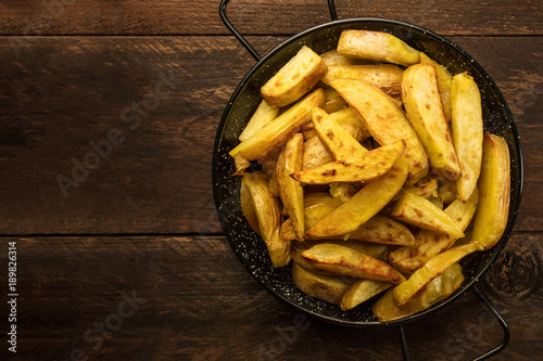 Crunchy roasted potatoes in skillet on dark rustic texture