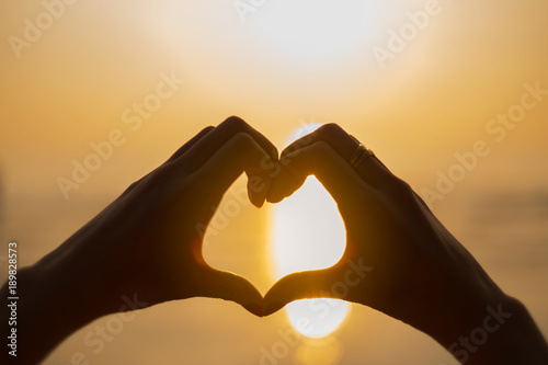Woman hand heart shape in sunset on the beach