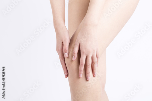 Woman holding sore knee, on white background.  © ddukang