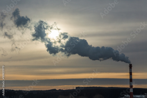 An industrial view of a sunrise in the city. Smoke from the pipe covers the sunrise