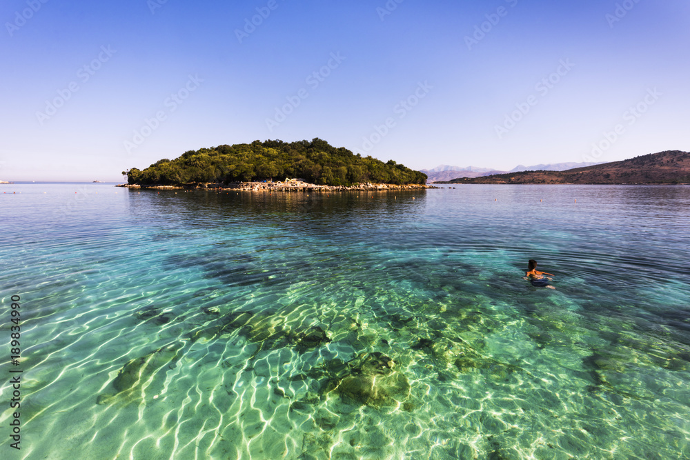 Fototapeta premium Ksamil Beach - Sportive man swimming to an idyllic island in sunrise atmosphere, Ksamil, Albania, Europe