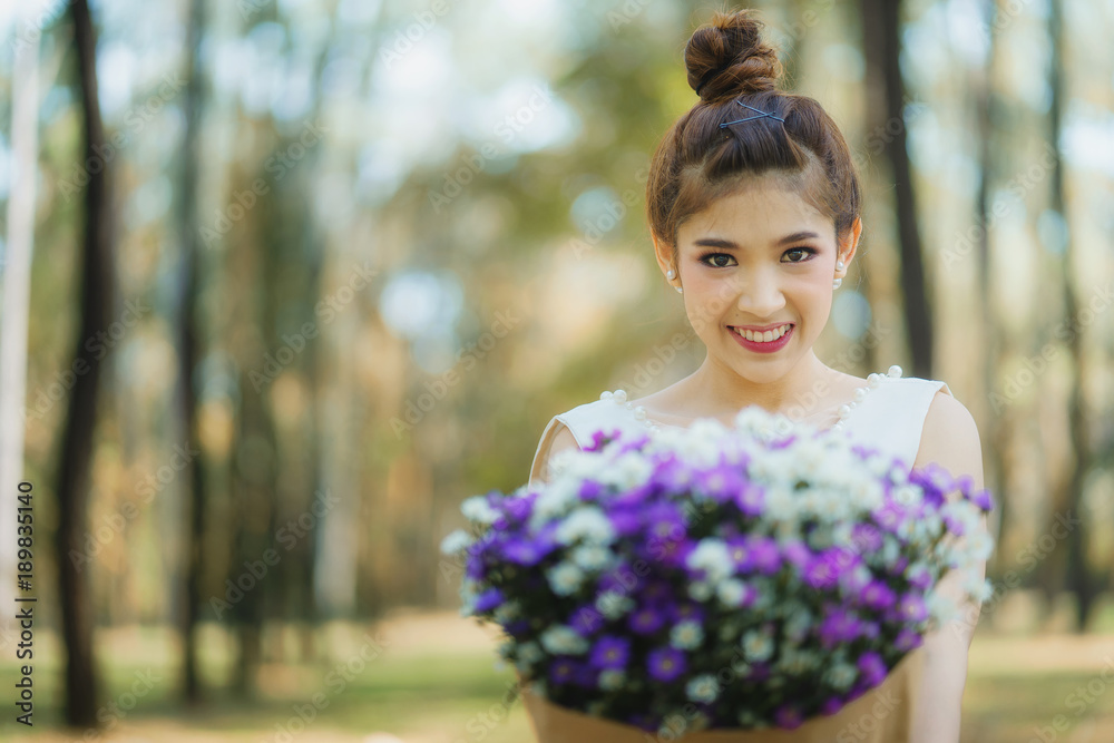 Beautiful young happy bride standing near the autumn tree in a park and holding a beautiful bouquet. Beautiful young happy bride standing near the autumn tree in a park and holding a beautiful bouquet.