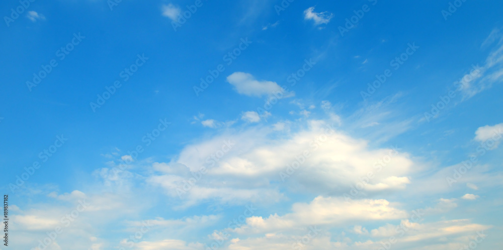 Light cumulus clouds against the blue sky. Wide photo.