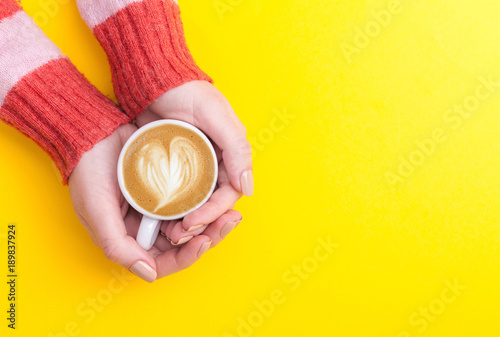 girl's hands holding coffee cup. flat lay, top view.