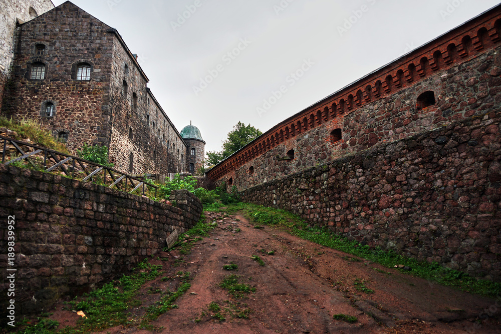 View of the walls and buildings inside the fortress/Inside the fortress, buildings and walls are visible to the left and to the right. Up comes a dirt path. Vyborg, Russia, Leningrad region, history