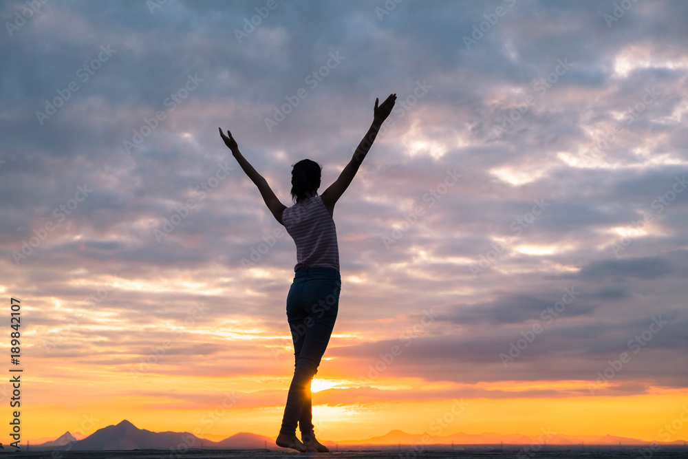 Silhouette of free woman enjoying freedom feeling happy at sunset. Serene relaxing woman in pure happiness