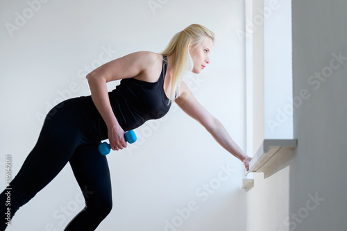 blonde girl doing exercise with Dumbbell in gym