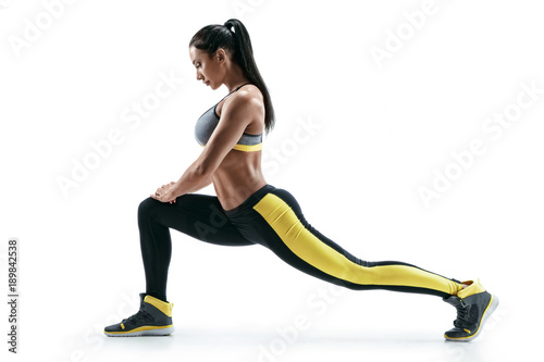 Fototapeta Naklejka Na Ścianę i Meble -  Fitness woman doing stretching workout. Full length shot of young woman on white background. Stretching and motivation