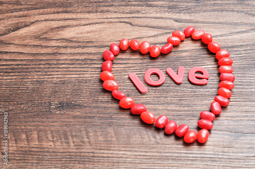 A heart shape made out of red jelly beans and the word love