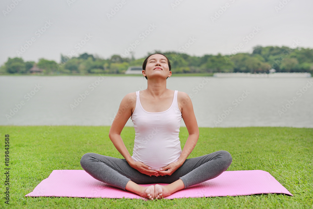 Pregnant woman doing yoga in the public park.