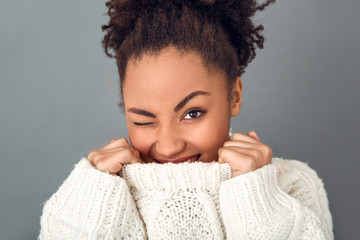 Young african woman isolated on grey wall studio winter concept wink