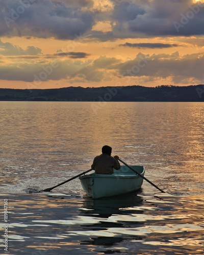 A man rowing at sunset. Ebeltoft harbour, Denmark.