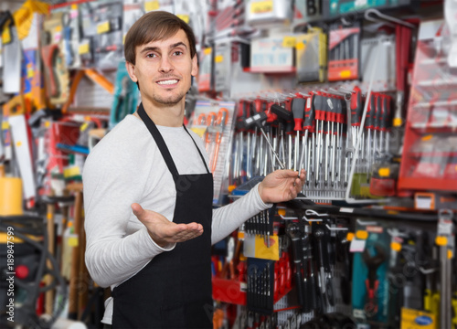 Φωτογραφία amiable young salesman in apron with tools