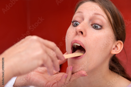 Nahaufnahme junge Frau mit Mundspatel auf der Zunge