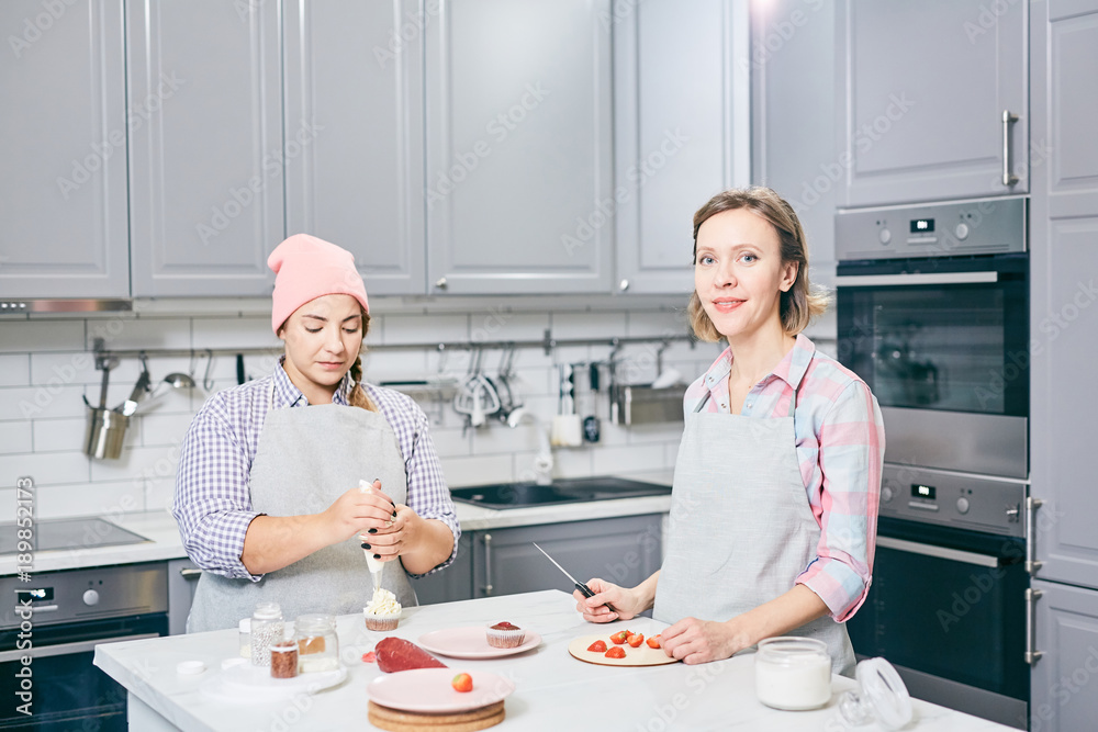 Two professionals cutting fresh strawberries and making whipped cream to decorate cakes Two professionals cutting fresh strawberries and making whipped cream to decorate cakes
