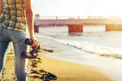 Unrecognizable Young Girl Standing On The Shore And Holding Binoculars, Rear View. Search Scout Travel Concept