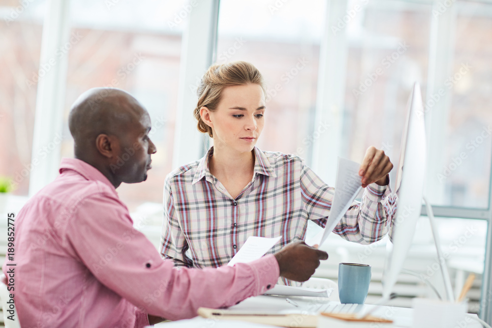 Intercultural office managers or economists reading financial documents at meeting Intercultural office managers or economists reading financial documents at meeting