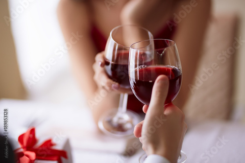 Beautiful couple celebrating Valentine`s day in restaurant, drinking wine, sharing gifts and enjoying each other.