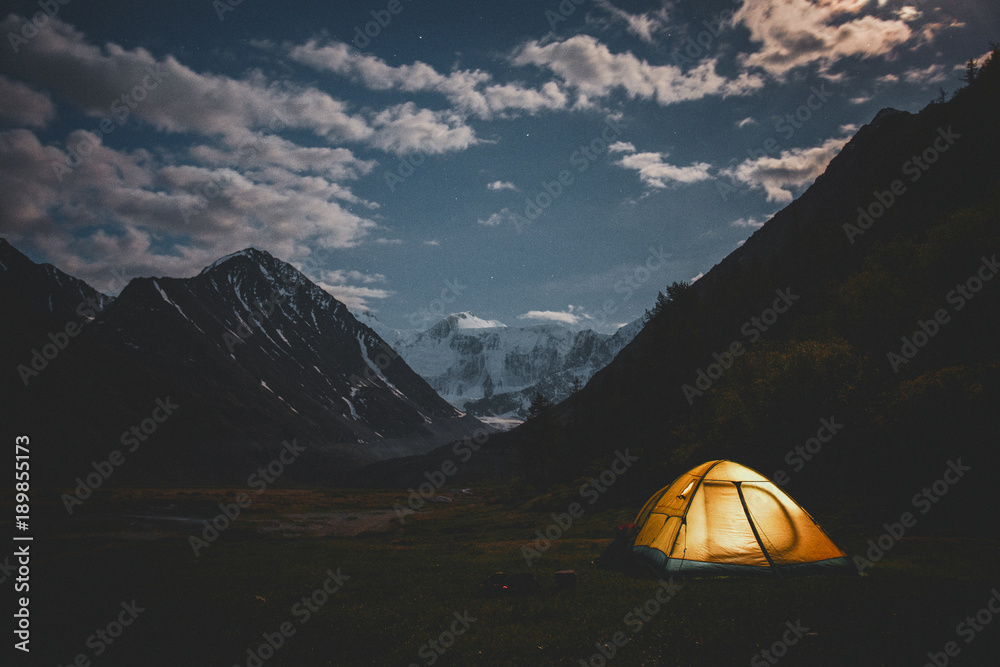 Tent among mountains in a quiet summer night
