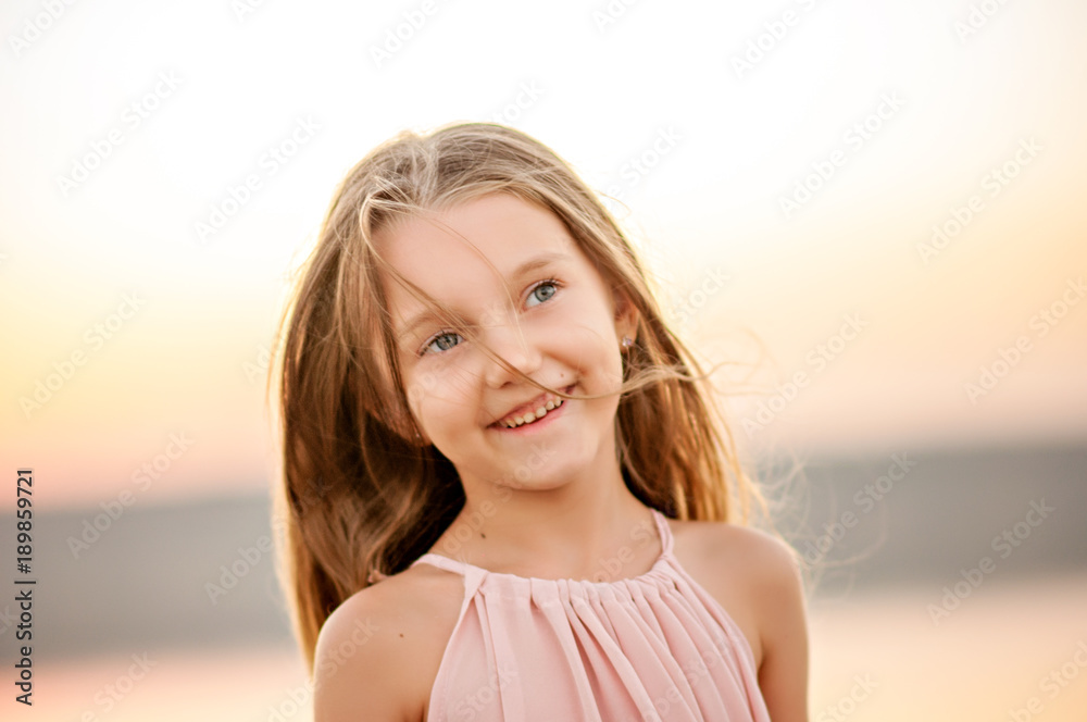 Portrait of a beautiful girl with long hair. Smiling at sunset.
