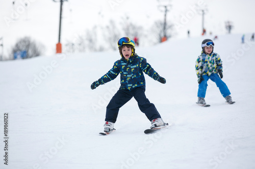 Cute little preschool child in blue jacket, skiing happily on a sunny day