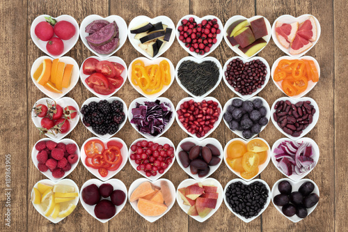 Healthy diet food concept with super health promoting properties in heart shaped bowls, high in antioxidants, anthocyanins, vitamins and minerals on rustic wood background. Top view.