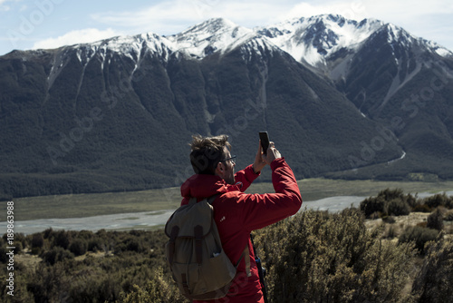 Hombre joven tomando fotos con su smartphone en un paisaje de montaña