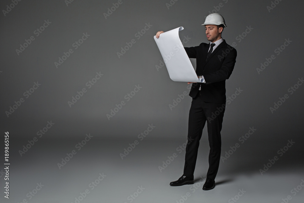 Full length portrait of serene unshaven architect looking at project. Job concept. Copy space Full length portrait of serene unshaven architect looking at project. Job concept. Copy space