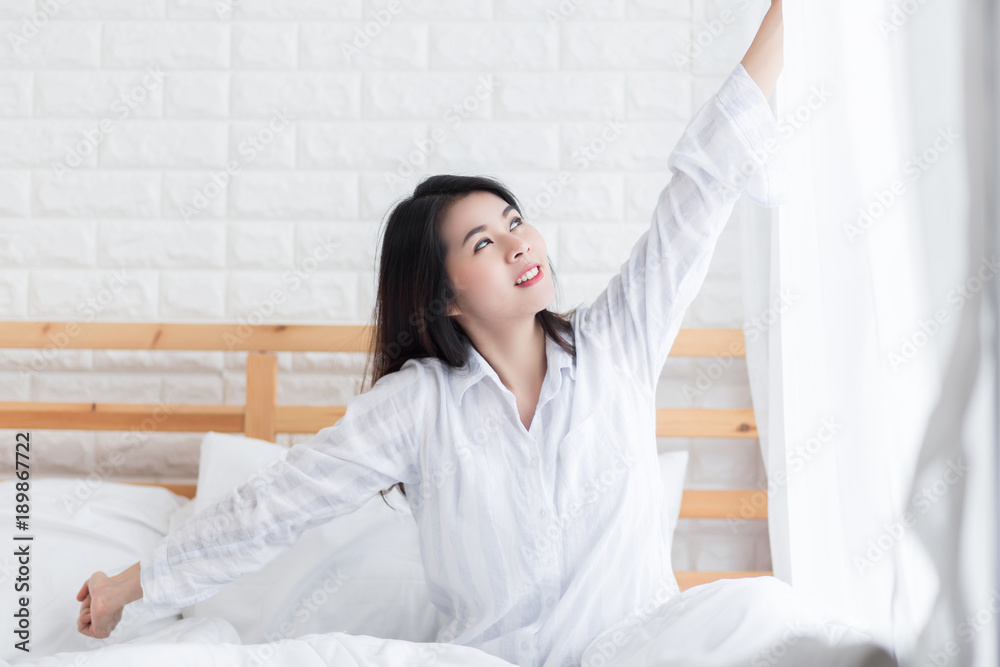 Beautiful smilling woman waking up in her bed in the bedroom, she is stretching and smiling in early morning. Beautiful smilling woman waking up in her bed in the bedroom, she is stretching and smiling in early morning.