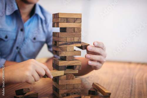 Images of hand of businesspeople placing and pulling wood block on the tower  Alternative risk concept  plan and strategy in business  Risk To Make Business Growth Concept With Wooden Blocks