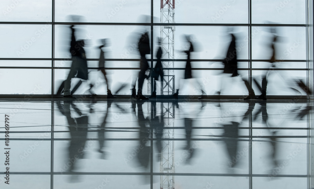© Yakobchuk Olena - Travel concept. Blurred terminal lounge with walking tourists. They are carrying suitcases. Full length