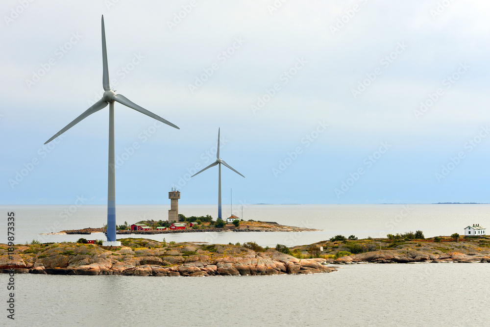 Wind Turbines and houses on rocky shores of Aland Islands on sunset. Finland