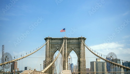 View of Brooklyn Bridge towers over blue sky with Manhattan skyline on background, in New York City